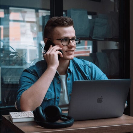 Germans Frolovs on a phone call while working on his laptop in a cafe
